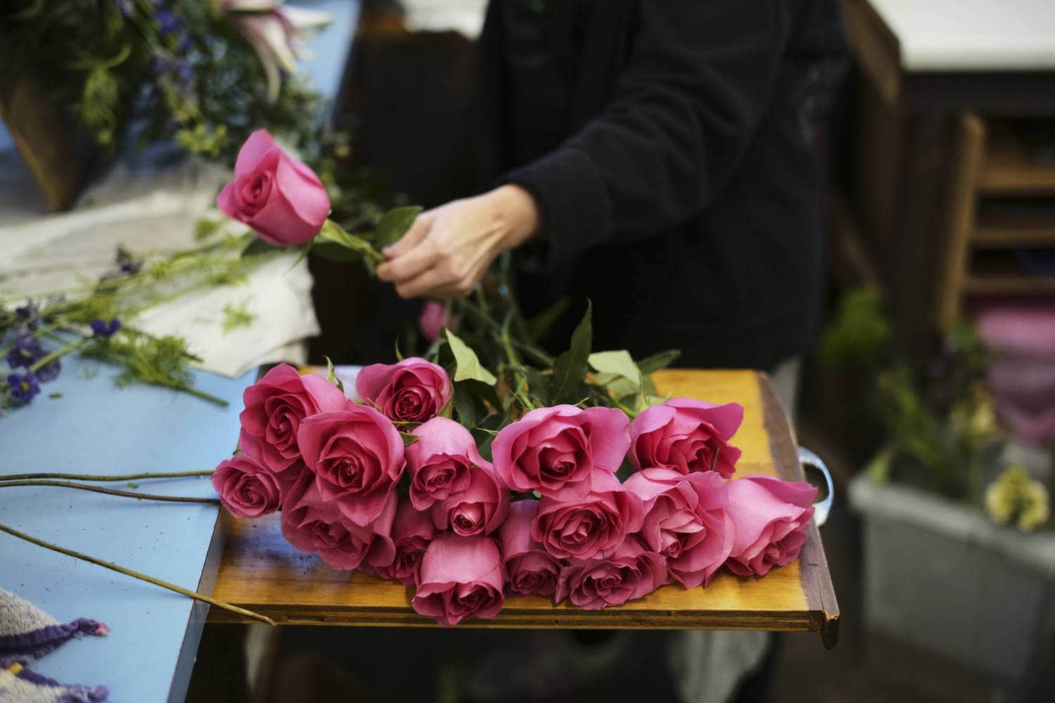 local florist with pink roses designing custom bouquet of flowers for valentine's day