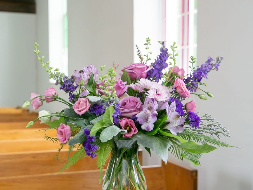 Amethyst tribute bouquet with lavender roses and chrysanthemums in glass vase by Studley Flower Gardens