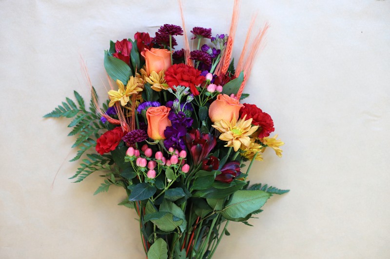 Radiant Dusk wrapped bouquet with purple and red blooms by Studley Flower Gardens