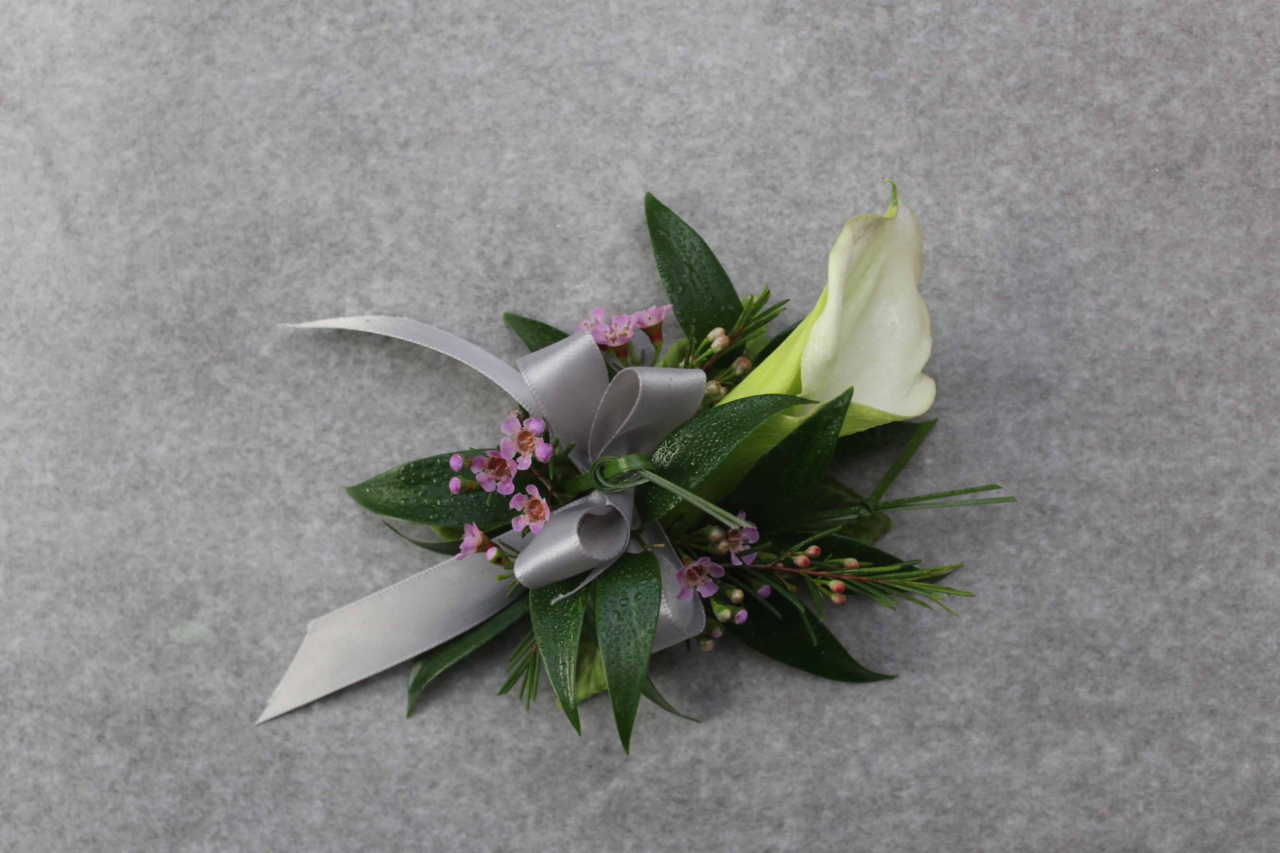 White calla lily corsage with textured greenery by Studley Flower Gardens
