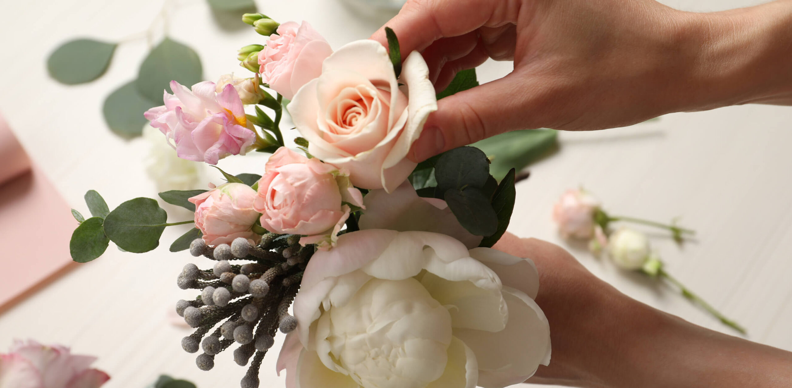 Hands putting together a bouquet of flowers for a wedding